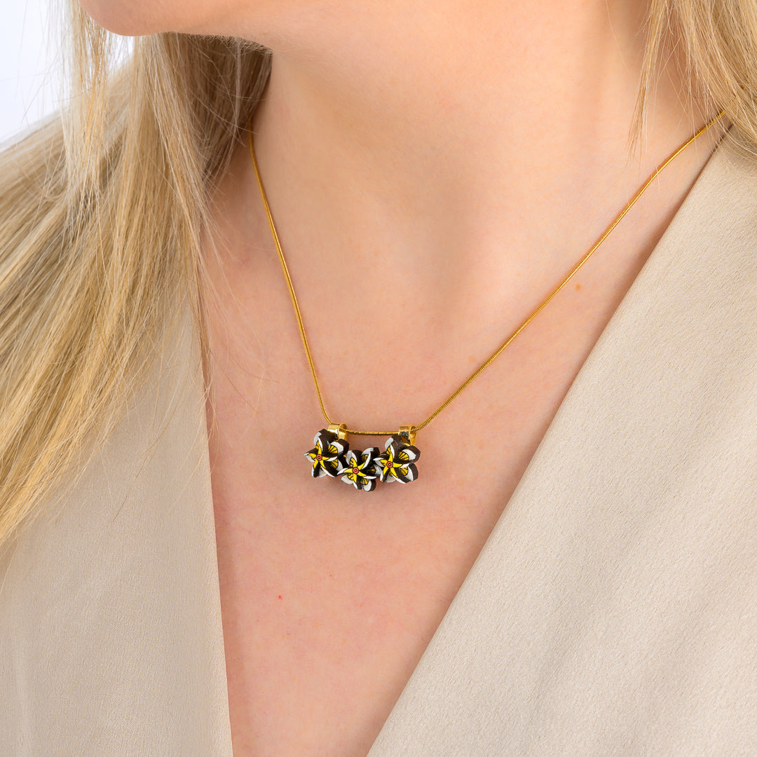 Paguro Upcycle reclaimed wood necklace with floral design worn on a woman in beige top