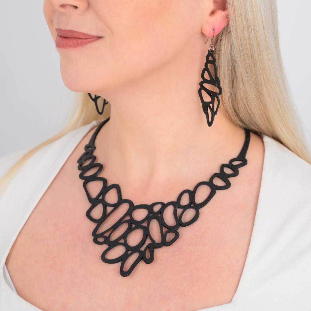 Paguro Upcycle black recycled rubber earrings with matching necklace worn by woman