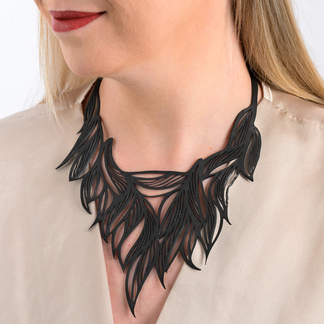Paguro Upcycle black recycled rubber necklace with intricate leaf design worn around neck