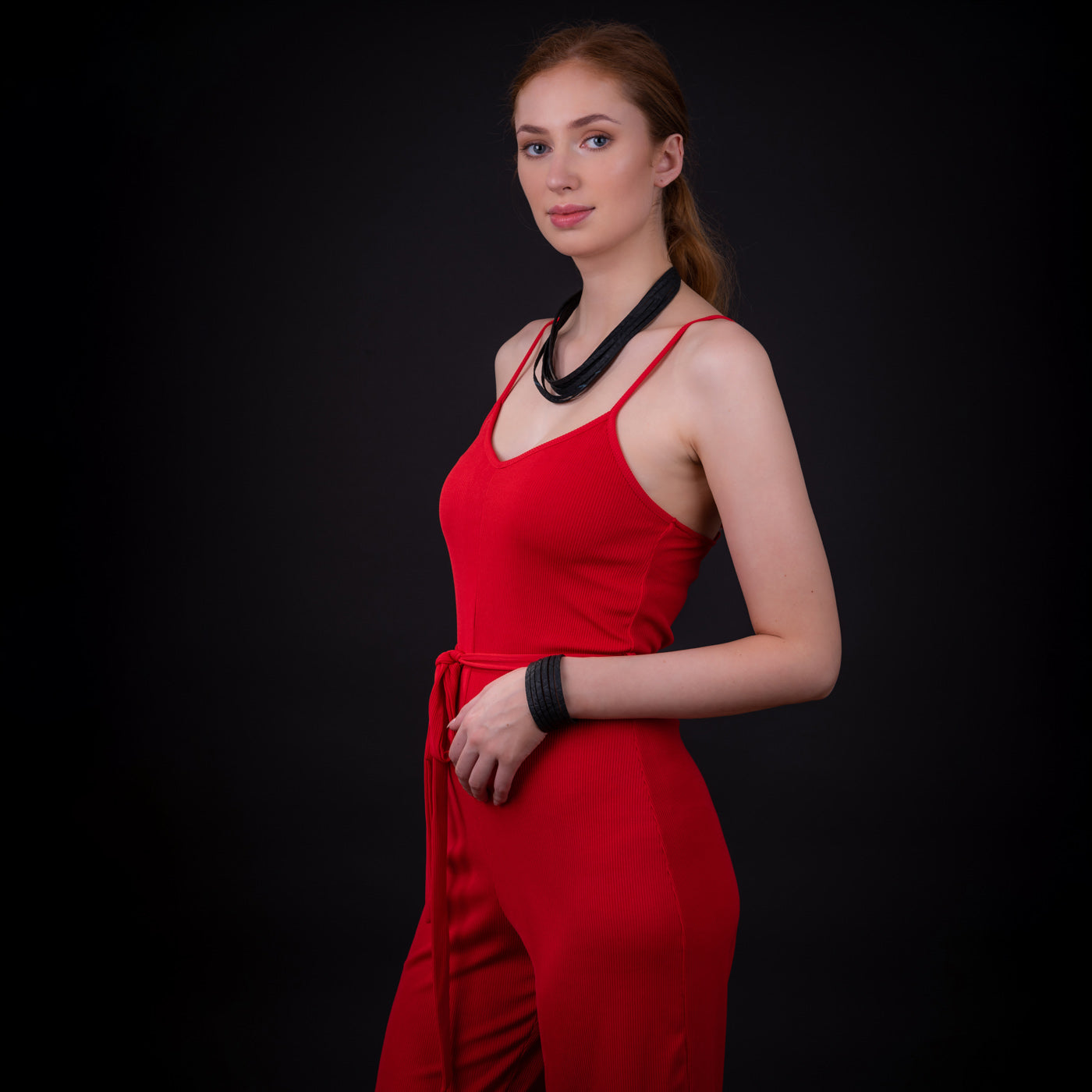 Woman in red outfit wearing a black recycled rubber bracelet and matching necklace from Paguro Upcycle